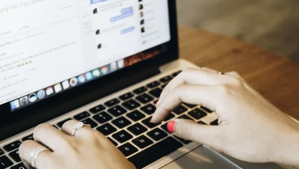 Manos escribiendo en una laptop con una aplicación de mensajería abierta