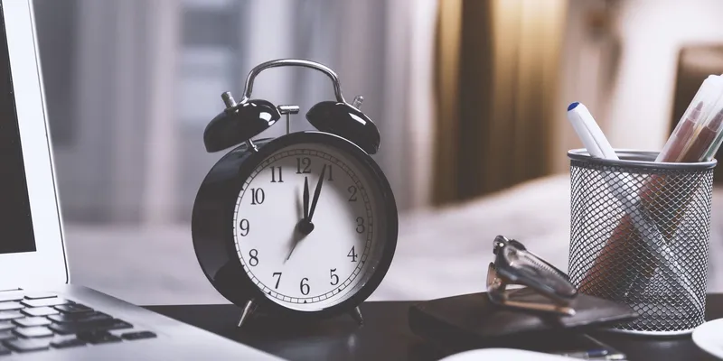 Reloj despertador junto a una laptop en un escritorio de oficina