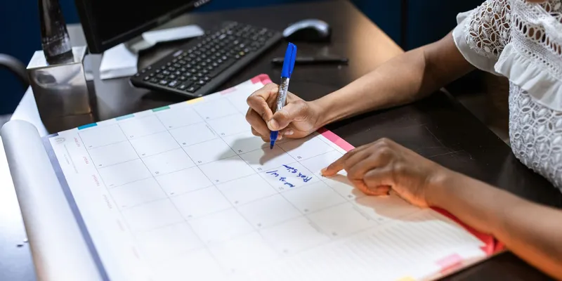 Persona anotando en un calendario de escritorio