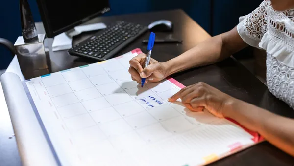 Persona anotando en un calendario de escritorio