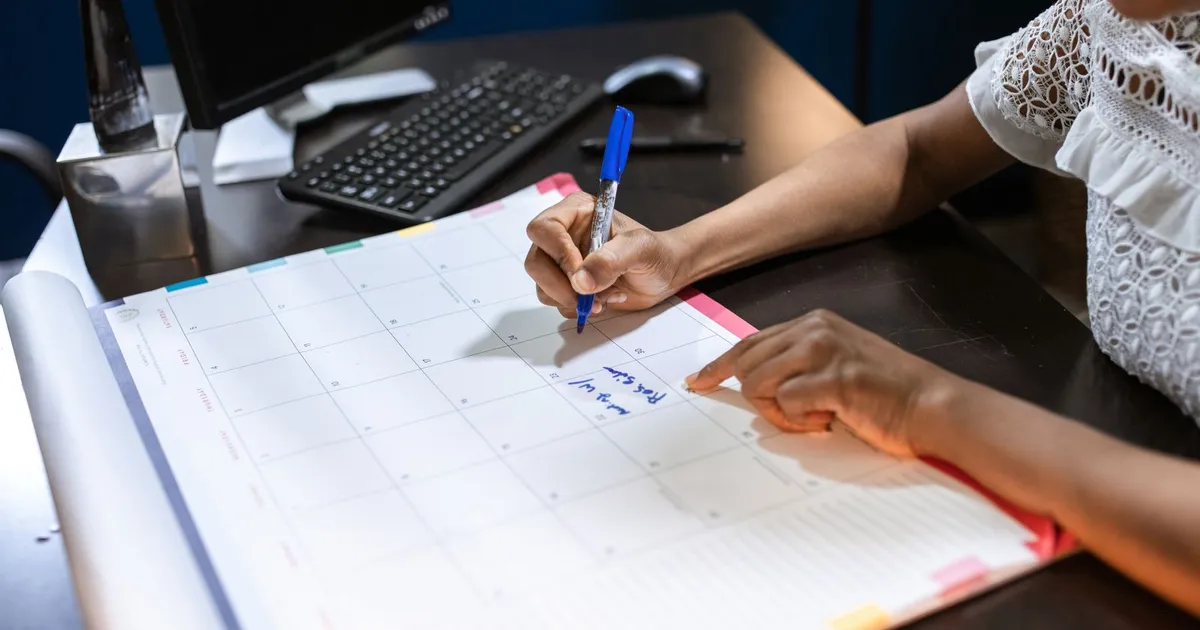 Persona anotando en un calendario de escritorio